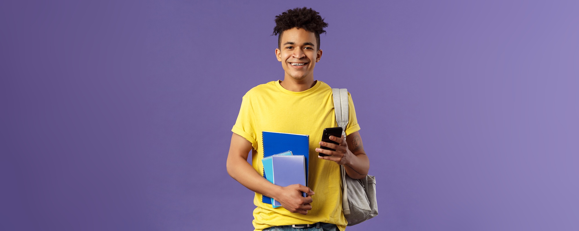 Back to school, university concept. Portrait of cheerful young handsome male student wearing backpack on shoulder, hold notebooks and studying books, texting friend mobile phone